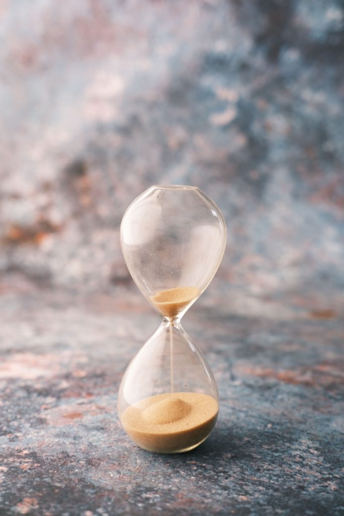 An elegant hourglass on a decorative textured surface, symbolizing the passage of time.