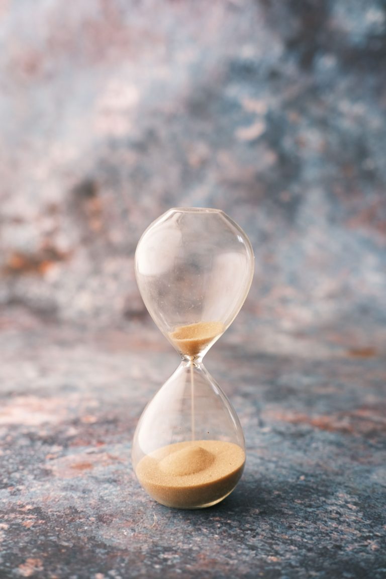 An elegant hourglass on a decorative textured surface, symbolizing the passage of time.